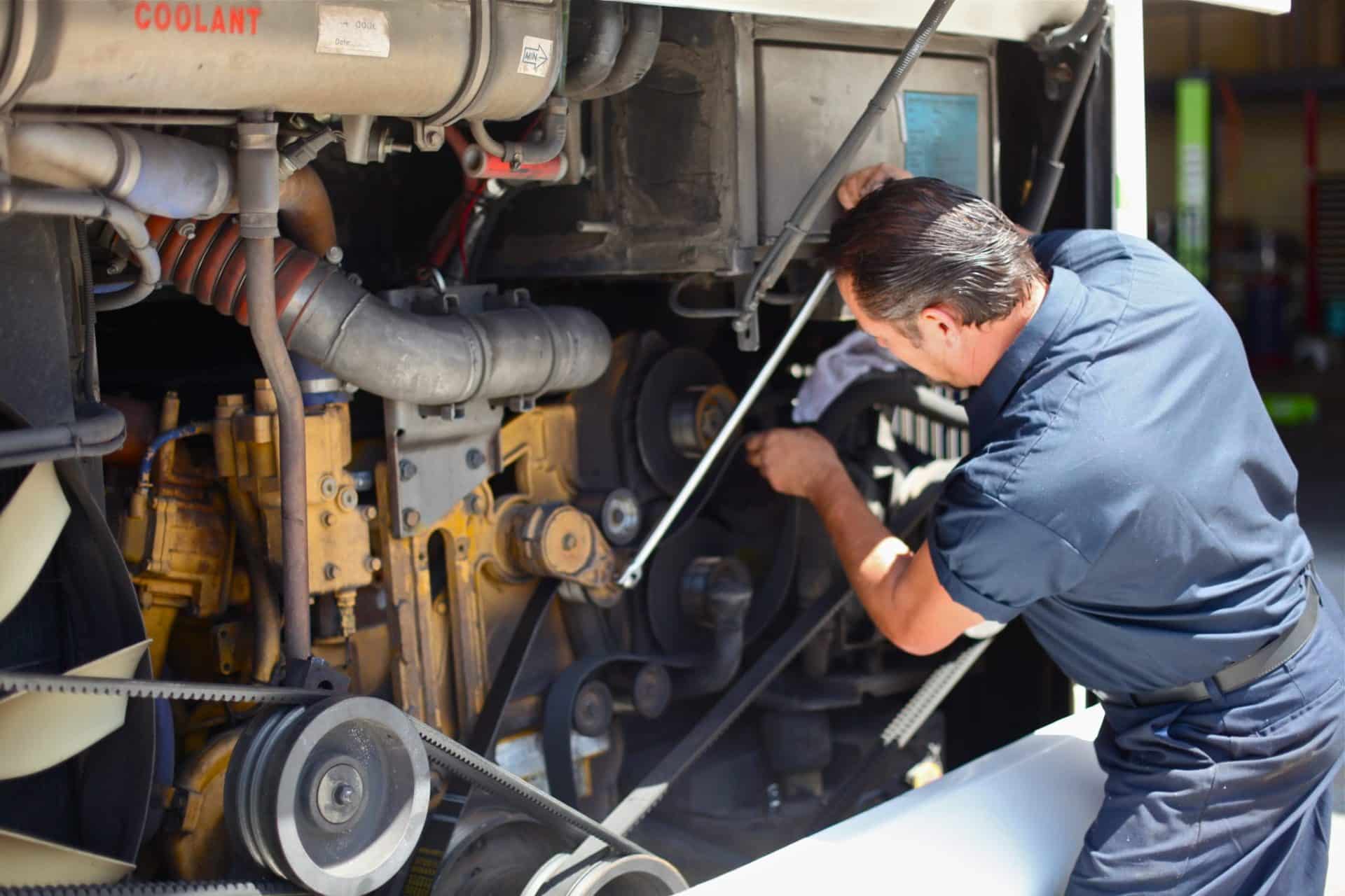 TCS employee working on bus mechanics inside engine