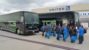 UCLA basketball team disembarking at airport in front of black tcs charter buses