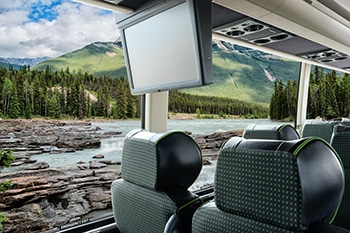 Charter bus interior showcasing leather seats dvd screen and outside window with river and mountain landscapes